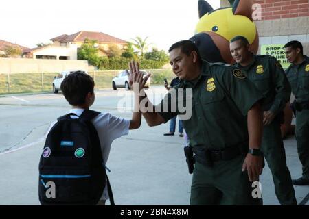 LAREDO, Texas – mit einem Willkommen zurück und einem High-Five, US-Grenzpatrouillen Agenten des Laredo Sector Border Community Liaison Program begrüßt Schüler zurück zur Schule in der Gegend Grundschulen in United Independent School District. Agenten waren an den Eingängen von Francisco Farias Elementary und Colonel Santos Benavides Elementary, um die Studenten zu treffen und zu begrüßen, als sie am 14. Und 16. August auf dem Campus ankamen, um das Laredo Sector High Five Programm zu initiieren. Die Studenten waren überrascht und begeistert, die Agenten zu treffen und Ringo, die Grenzpatrouille des Sektors Laredo, zu sehen Stockfoto