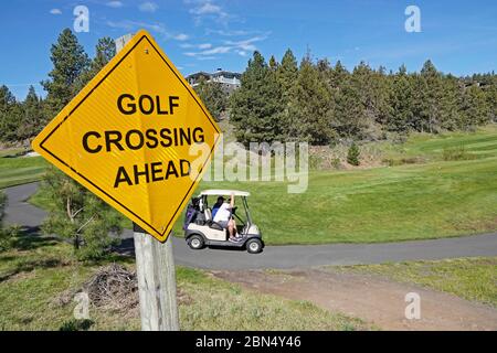 Golfer in einem batteriebetriebenen Golfwagen gehen von Loch zu Loch auf einem Golfplatz in Bend, Oregon. Stockfoto