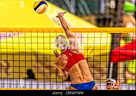 Eine Volleyballspielerin erhebt sich am Netz, um den Ball nach unten zu spike Stockfoto