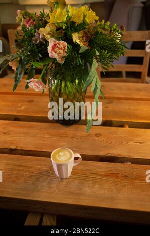 Eine Tasse heißen Cappuccino auf einem Holztisch. Cappuccino mit Latte Art in einer schönen Tasse auf dem Tisch in einem Café. Selektiver Fokus. Zu Hause. Zeit fo Stockfoto