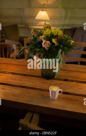 Eine Tasse heißen Cappuccino auf einem Holztisch. Cappuccino mit Latte Art in einer schönen Tasse auf dem Tisch in einem Café. Selektiver Fokus. Zu Hause. Zeit fo Stockfoto