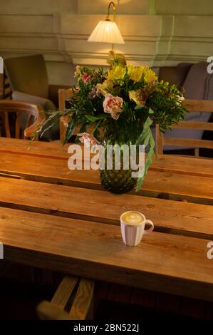 Eine Tasse heißen Cappuccino auf einem Holztisch. Cappuccino mit Latte Art in einer schönen Tasse auf dem Tisch in einem Café. Selektiver Fokus. Zu Hause. Zeit fo Stockfoto