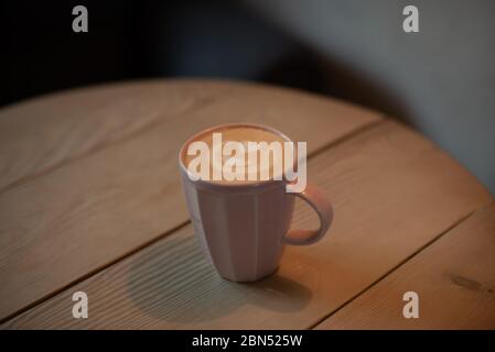 Eine Tasse heißen Cappuccino auf einem Holztisch. Cappuccino mit Latte Art in einer schönen Tasse auf dem Tisch in einem Café. Selektiver Fokus. Zu Hause. Zeit fo Stockfoto