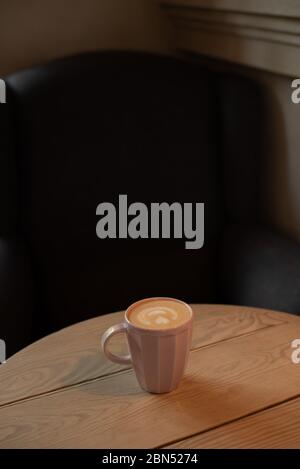 Eine Tasse heißen Cappuccino auf einem Holztisch. Cappuccino mit Latte Art in einer schönen Tasse auf dem Tisch in einem Café. Selektiver Fokus. Zu Hause. Zeit fo Stockfoto