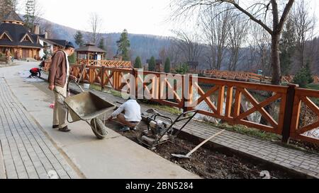Verlegung von grauen Pflasterplatten auf dem Stadtplatz, Reparatur des Bürgersteiges. Professionelle Maurer installieren neue Fliesen auf einem Fundament aus gesäumtem Sand Stockfoto