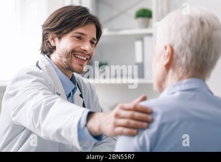 Freundlicher Geriater, der ältere Frau im Krankenhaus unterstützt Stockfoto
