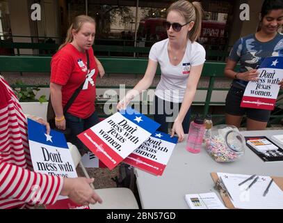 Austin Texas, USA, März 13 2012: Die junge Frau verteilt die Schilder „Don't Lead with Texas Women“, während der geplante Parenthood Tour-Bus in der Nähe des Campus der University of Texas hält. Die Organisation hofft, das Bewusstsein für die Kürzungen von Frauengesundheitsprogrammen zu schärfen, die sie der Regierung von Texas vorwirft. Rick Perry. Planned Parenthood's Texas Clinics verlieren am 14. März die Finanzierung aus dem Texas Medicaid Women's Health Program, das rund 130.000 Frauen mit niedrigem Einkommen dient. ©Marjorie Kamys Cotera/Daemmrich Photography Stockfoto