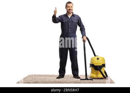 Ganzkörperportrait eines Hausmeisters in Uniform mit einem Staubsauger auf einem Teppich stehend mit Daumen nach oben isoliert auf weißem Hintergrund Stockfoto