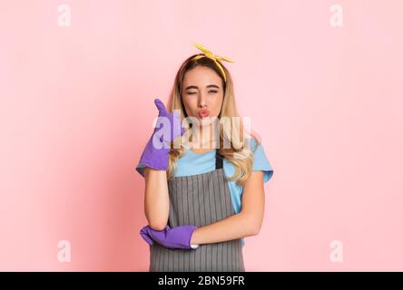 Hausfrau macht Kuss Lippen, zeigt Zeichen gut mit der Hand in Handschuhen Stockfoto