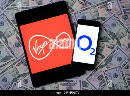 Stone / Großbritannien - Mai 12 2020: Virgin Media und O2 Telefonica Logos auf den mobilen Geräten auf Dollar platziert. Konzept für potentielles Multimilliardenpotenzial Stockfoto