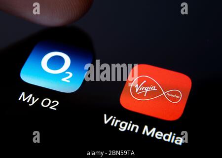 Stone / Großbritannien - Mai 12 2020: Virgin Media und My O2 Apps auf dem Smartphone-Bildschirm und Fingerdruck auf eine von ihnen. Makro. Konzept für Potential m Stockfoto