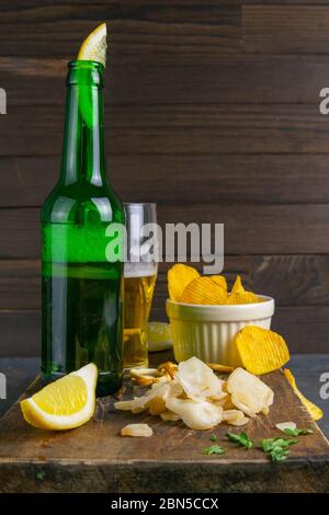 Getrockneter Oktopus mit Bier, Zitrone und Kartoffelchips auf dunklem Holzbrett. Snack auf Fisch mit Bier. Nahaufnahme Stockfoto