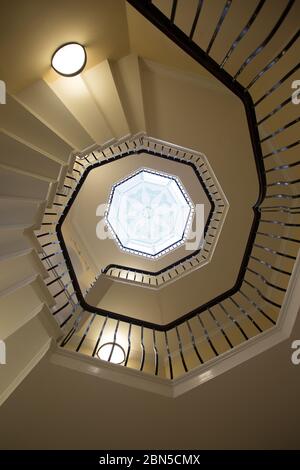 Blick vom Boden einer Wendeltreppe mit Blick auf den Mittelpunkt im Dach eines Art-Deco-Fensters, Stockfoto
