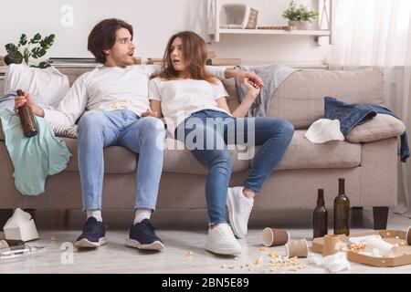 Schockiert Paar Aufwachen In Chaotisch Zimmer Nach Feier Party Zu Hause Stockfoto