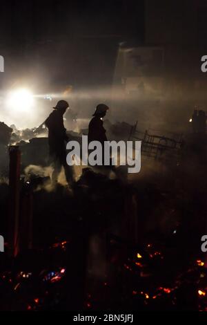 Die Feuerwehr von Jakarta arbeitet nach einer Schlacht in einer dichten Nachbarschaft zwischen Trümmern Mitglieder der Feuerwehr von Jakarta Abkühlung der Gegend, nachdem ein Brandunfall sich ausbreitet und Hunderte von Häusern in einer dichten Nachbarschaft in Penjaringan, Nord-Jakarta, Jakarta, Indonesien verbrennt. Archivbild. Februar 2011. Foto: Reynold Sumaiku Stockfoto