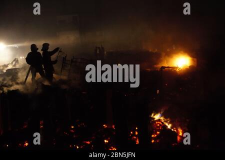 Die Feuerwehr von Jakarta arbeitet nach einer Schlacht in einer dichten Nachbarschaft zwischen Trümmern Mitglieder der Feuerwehr von Jakarta Abkühlung der Gegend, nachdem ein Brandunfall sich ausbreitet und Hunderte von Häusern in einer dichten Nachbarschaft in Penjaringan, Nord-Jakarta, Jakarta, Indonesien verbrennt. Archivbild. Februar 2011. Foto: Reynold Sumaiku Stockfoto