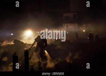 Die Feuerwehr von Jakarta arbeitet nach einer Schlacht in einer dichten Nachbarschaft zwischen Trümmern Mitglieder der Feuerwehr von Jakarta Abkühlung der Gegend, nachdem ein Brandunfall sich ausbreitet und Hunderte von Häusern in einer dichten Nachbarschaft in Penjaringan, Nord-Jakarta, Jakarta, Indonesien verbrennt. Archivbild. Februar 2011. Foto: Reynold Sumaiku Stockfoto