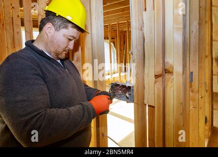 Elektriker Kabelführung in elektrischen Stecker, Steckdosen an der Wand in einem Holzbalken Rahmenhaus Stockfoto