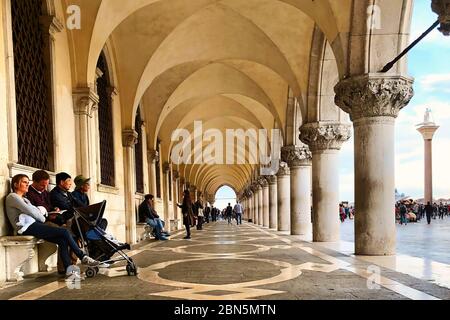 Touristen ruhen sich auf dem Korridor des Duks Palace auf dem Markusplatz in Venedig in Italien aus. Stockfoto Touristen ruhen sich auf dem Korridor des Duks Palace auf dem Markusplatz in Venedig in Italien aus. Stockfoto