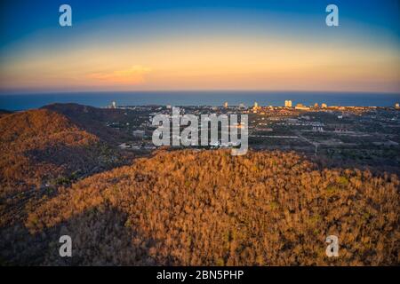 Dieses einzigartige Foto zeigt die herbstliche Hügellandschaft auf dem hin lek fai bei Sonnenuntergang! Der wunderschöne goldene Himmel über der Stadt Hua hin im Hintergrund Stockfoto