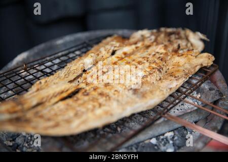 Koreanischer traditioneller Fisch wird auf einem Holzkohlefeller auf einem kleinen Drahtrack gegrillt Stockfoto