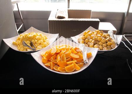 Orangen, Bananen und Ananas in Scheiben geschnitten auf einer großen Büffetschüssel Stockfoto