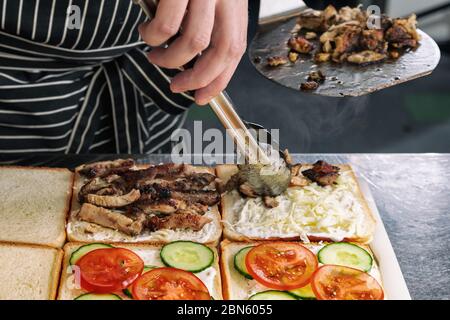 Nahaufnahme von leckeren Sandwiches mit gegrilltem Fleisch, Mayonnaise, Tomaten, Käse und Gurke Stockfoto