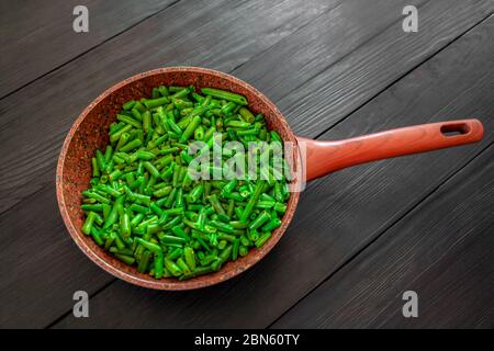 Gekochte grüne Bohnen in einer Pfanne auf schwarzem Holzgrund. Platz zum Kopieren. Draufsicht Stockfoto