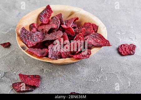 Ernährung gesundes Essen Konzept. Getrocknete Rübenschnitzel oder gebackene Rüben in einer Holzschale, auf grauem Betongrund. Bio-Naturkost. Kopierbereich. Stockfoto