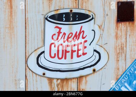 Frische Kaffee-Beschilderung in einer weißen Tasse an der Wand. Stockfoto