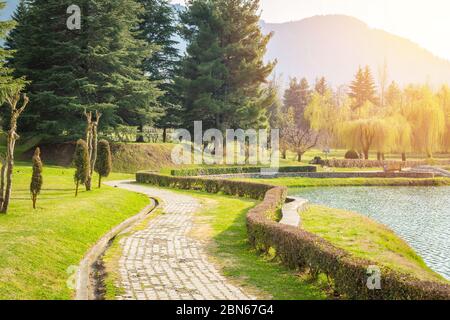 Steinweg in einem üppigen grünen Park entlang eines schönen Sees in Kaschmir. Dal See, Botanischer Garten Stockfoto