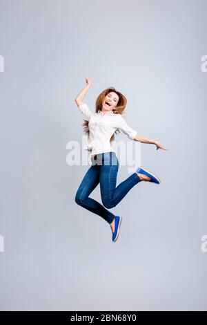 Glück, Traum, Spaß, Freude Konzept. Sehr aufgeregt glücklich Mädchen springt auf einem hellgrauen Hintergrund, tragen Casual Kleidung, Gesturing ein Friedenszeichen Stockfoto