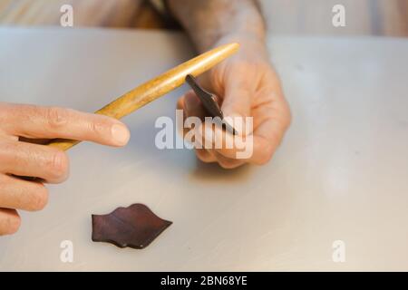 Lederrand Burnishing, Lederrand Finishing von handgefertigten Werkzeugen. Der Prozess der Herstellung einer Ledertasche handgefertigt. Der Handwerker näht ein Leder Stockfoto