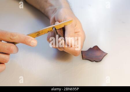 Lederrand Burnishing, Lederrand Finishing von handgefertigten Werkzeugen. Der Prozess der Herstellung einer Ledertasche handgefertigt. Der Handwerker näht ein Leder Stockfoto