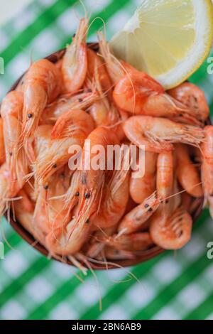 Schwarze Meer Garnelen. Frisch gekochte Seegrarnelen in einer Schüssel auf einem auf dem Hintergrund einer grün-weißen Tischdecke. Meeresboden. Sea Products Makro. Stockfoto