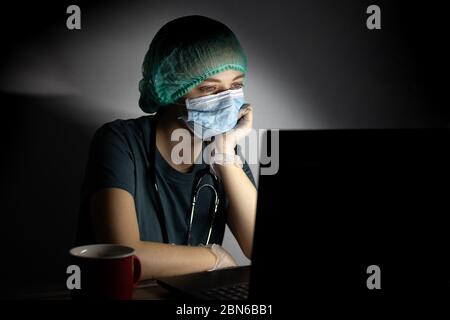 Kaukasische Frau Arzt Krankenschwester in chirurgischen Maske sieht müde, erschöpft in der Nacht wegen Covid Stockfoto