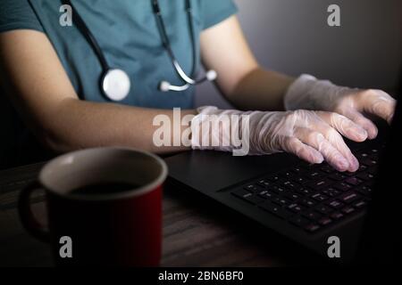 Die Hände des Arztes oder der Krankenschwester auf der Tastatur im Dunkeln. Lange Stunden oder Überstunden Arbeit der medizinischen Arbeiter Konzept. Stockfoto