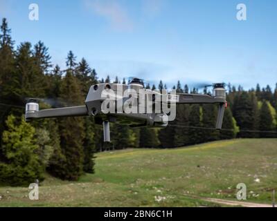 Eine Drohne wird in einem stationären Schweben vor der Kamera eingefangen. Die Drohne schwebt im Waldnaturgebiet der Schweiz. Stockfoto