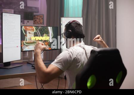 Junger Mann feiert seinen Sieg ein Online-Shooter-Spiele halten seine Fäuste fest. Stockfoto