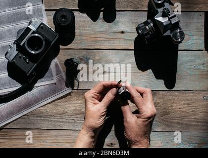 Draufsicht des Arbeitsraumes Fotografen mit analogen Kameras, Film, Linsen und Zubehör auf alten Holztisch Hintergrund Stockfoto