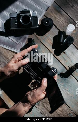 Draufsicht des Arbeitsraumes Fotografen mit analogen Kameras, Film, Linsen und Zubehör auf alten Holztisch Hintergrund Stockfoto