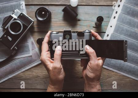 Draufsicht des Arbeitsraumes Fotografen mit analogen Kameras, Film, Linsen und Zubehör auf alten Holztisch Hintergrund Stockfoto