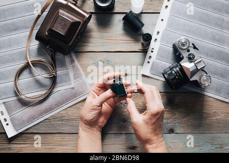 Draufsicht des Arbeitsraumes Fotografen mit analogen Kameras, Film, Linsen und Zubehör auf alten Holztisch Hintergrund Stockfoto