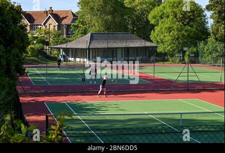 Brighton UK 13. Mai 2020 - Tennisspieler nehmen an den Plätzen im Queens Park Brighton früh am Morgen nach der Lockerung einiger Coronavirus Lockdown Maßnahmen in England. Einige Lockdown-Maßnahmen wurden in England von Boris Johnsons Regierung gelockert, einschließlich Tennis oder Golf während der Coronavirus COVID-19 Pandemie. : Credit Simon Dack / Alamy Live News Stockfoto