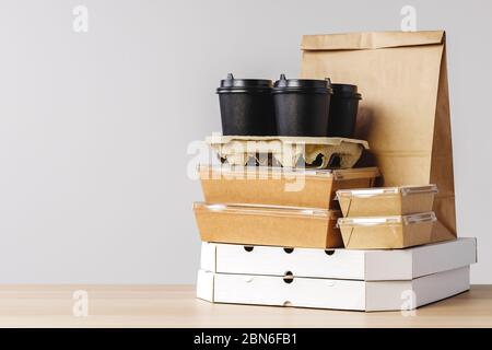 Viele verschiedene Take-out-Food-Container, Pizzakasten, Kaffeetassen und Papiertüten auf hellgrauem Hintergrund Stockfoto