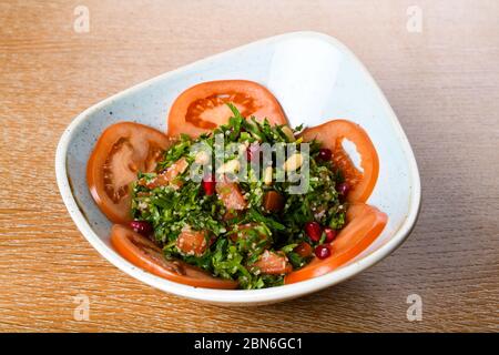Tabbouleh ist ein levantiner vegetarischer Salat, der hauptsächlich aus fein gehackter Petersilie, mit Tomaten, Minze, Zwiebeln, Bulgur und gewürzt mit Olivenöl, lemo, hergestellt wird Stockfoto