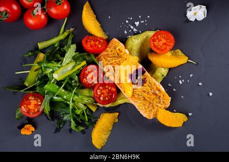 Frisches Lachsfilet, Salat mit Rucola, Mandarinorange, Kirschtomaten Stockfoto