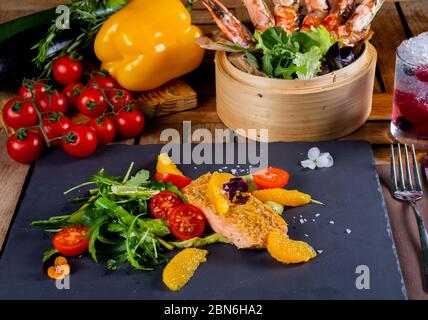 Frisches Lachsfilet, Salat mit Rucola, Mandarinorange, Kirschtomaten Stockfoto