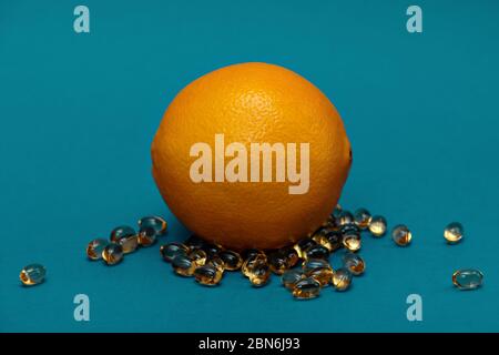 Vitamine mit Orange auf blauem Hintergrund. Omega Fischöl Stockfoto