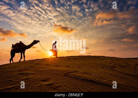 Kamelfahrer mit Kamelfiguren in den Dünen bei Sonnenuntergang. Jaisalmer, Rajasthan, Indien Stockfoto